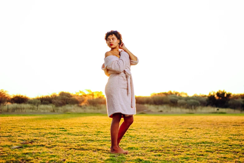 a woman stands in the grass with her hands to her face