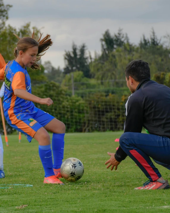 a man and a girl are playing soccer