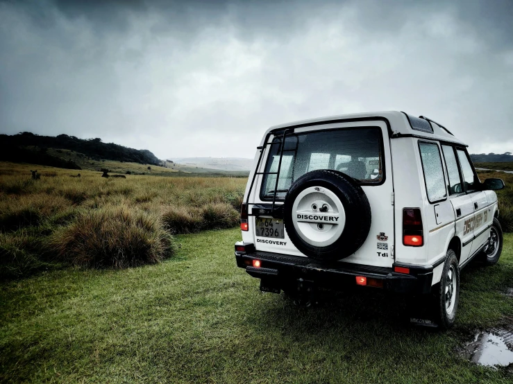 a white jeep parked in the middle of a field