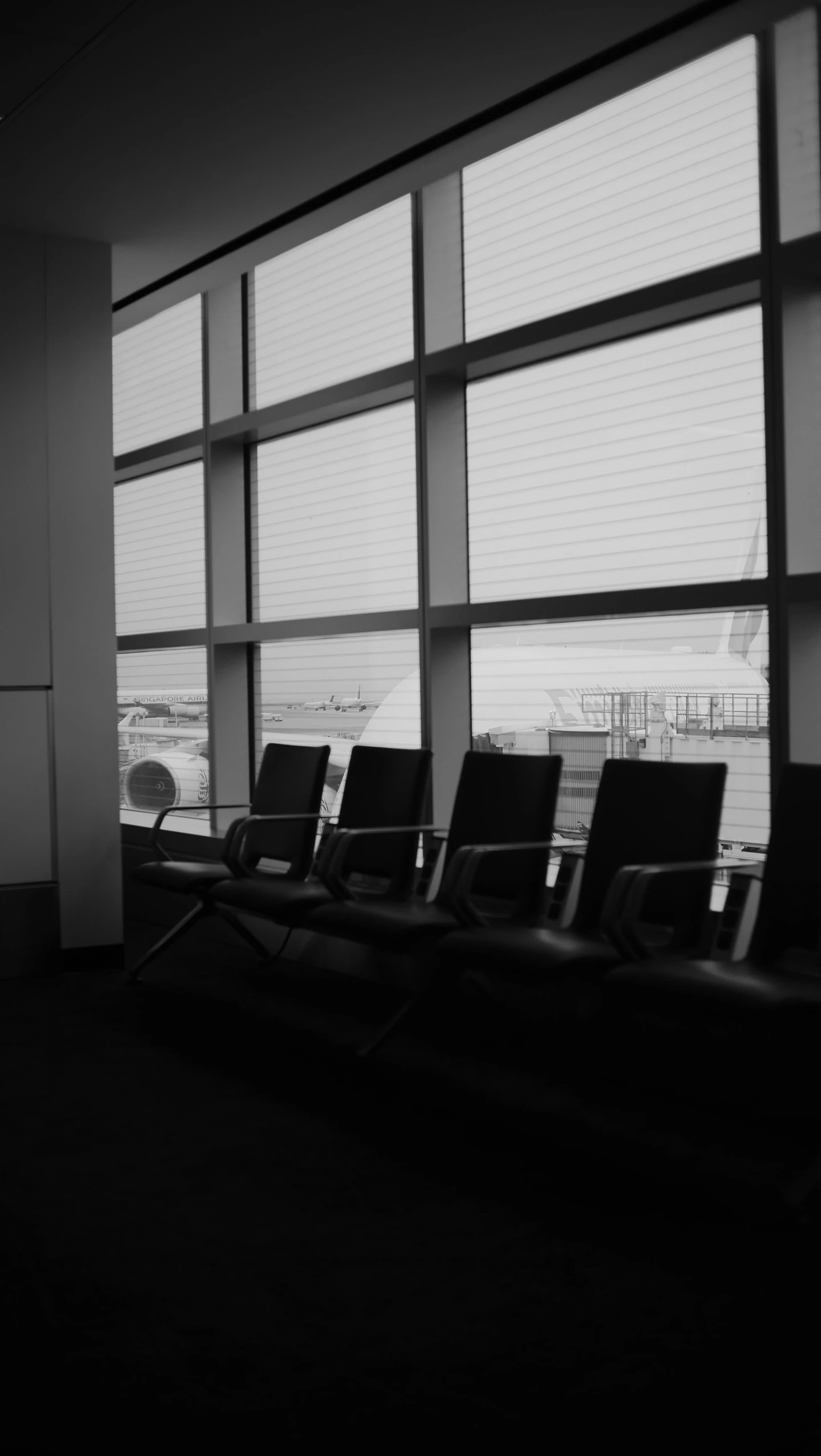 black and white po of an airport waiting area with lots of chairs in front of a large window