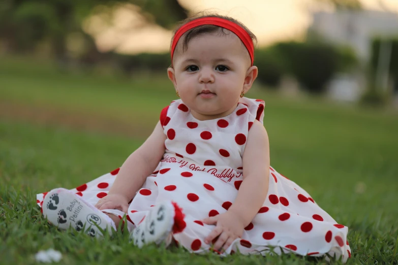 a cute little girl sitting in the grass