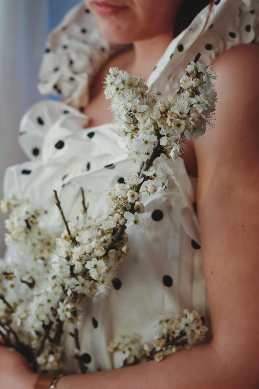 woman in polka dots dress holding bunch of flowers