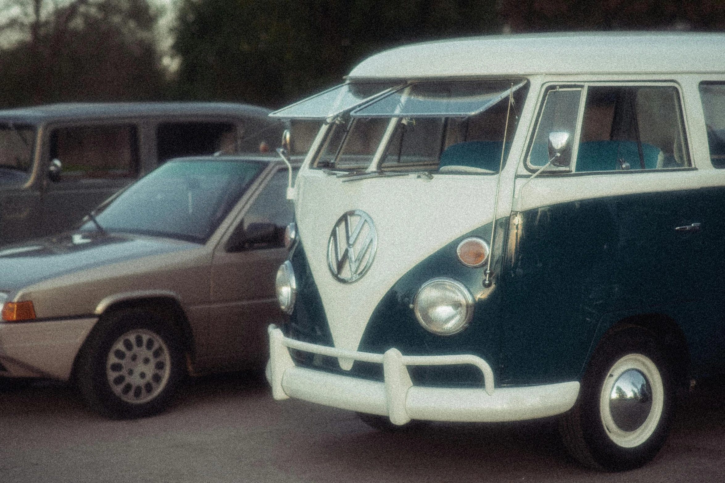 some cars are sitting in the parking lot and one has a bus