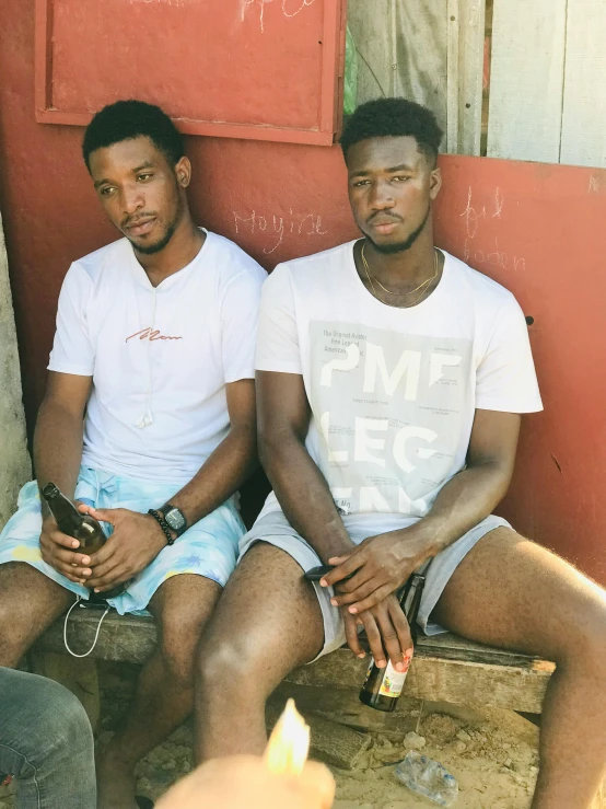 two young men sitting against a door on a bench