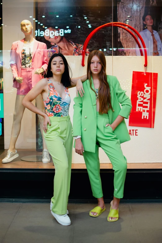 two women in bright clothes posing in front of a mannequin