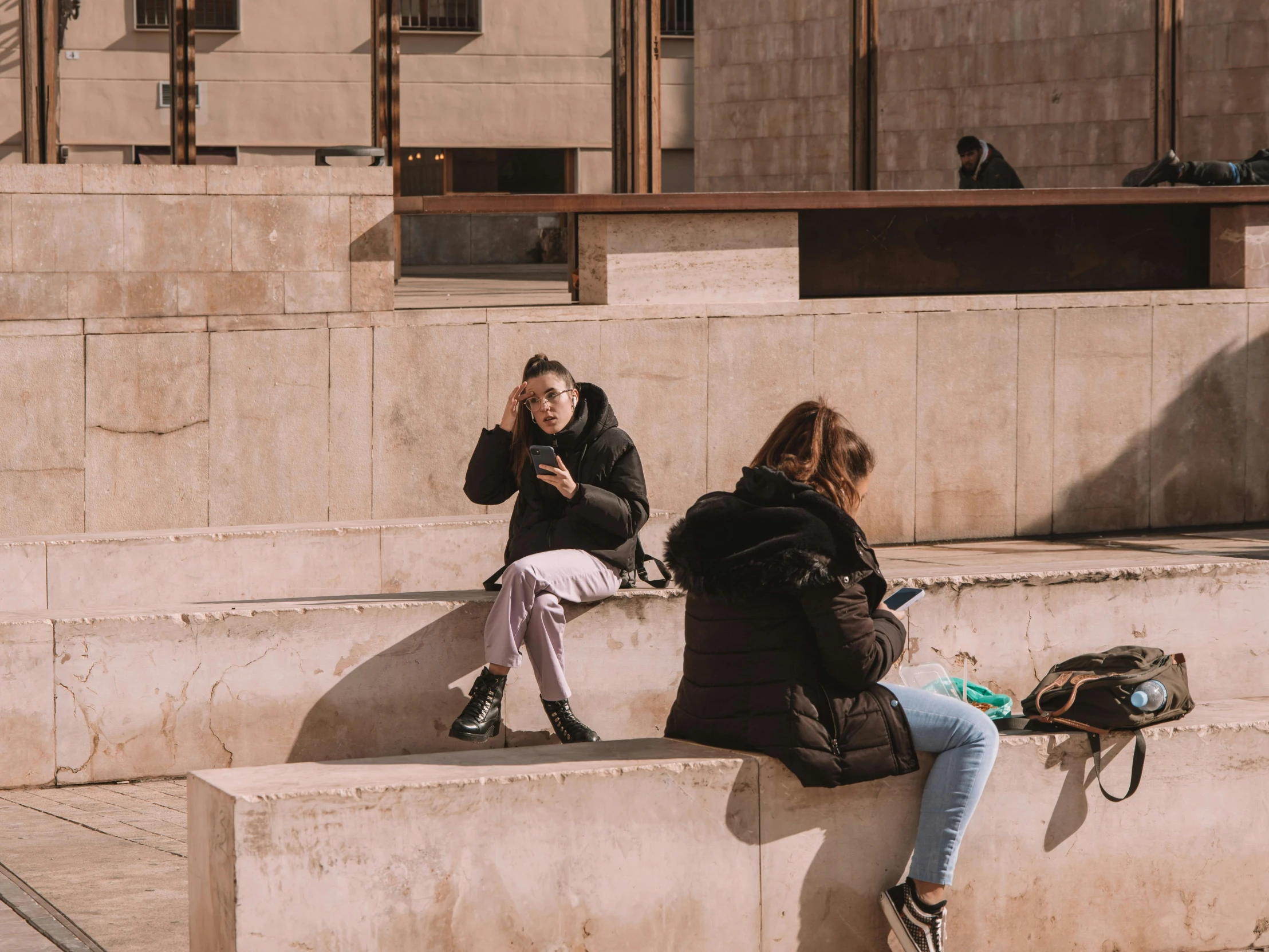 the two young women are sitting down on concrete blocks