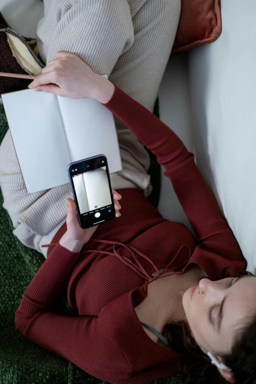 a woman with her phone in her hand while laying on a couch