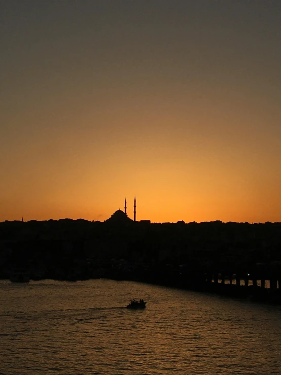 the sun setting and silhouettes an old building on a body of water