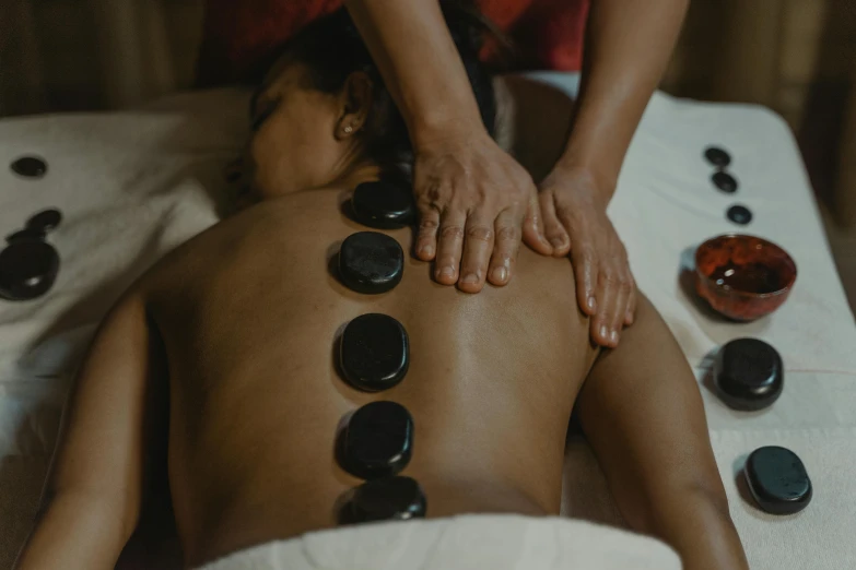 a man having massages and body stone stones on the side of his body