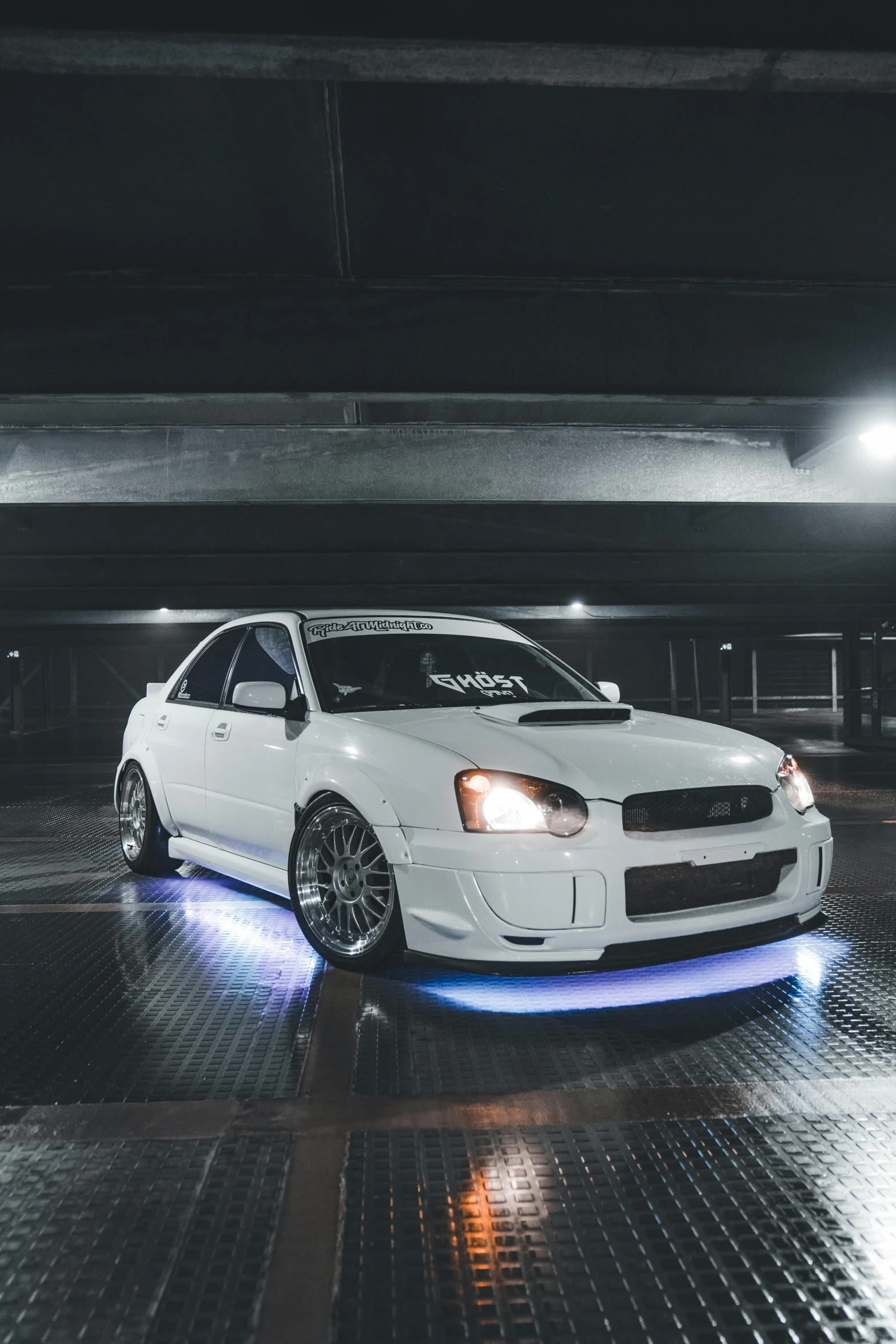 a white car is parked in an underground parking garage