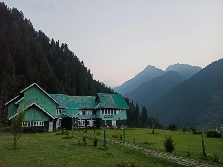 a blue house on a grassy area in front of a mountain