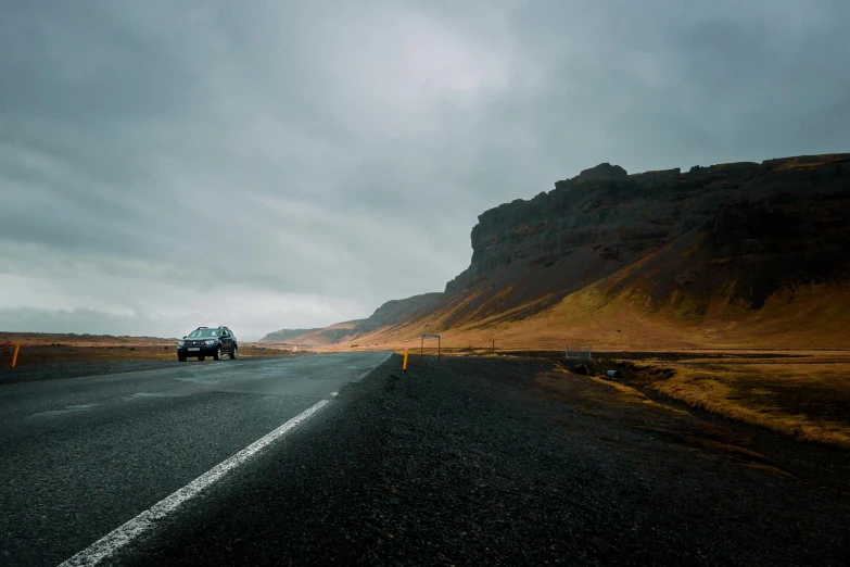 there is an suv driving down the road next to a hill