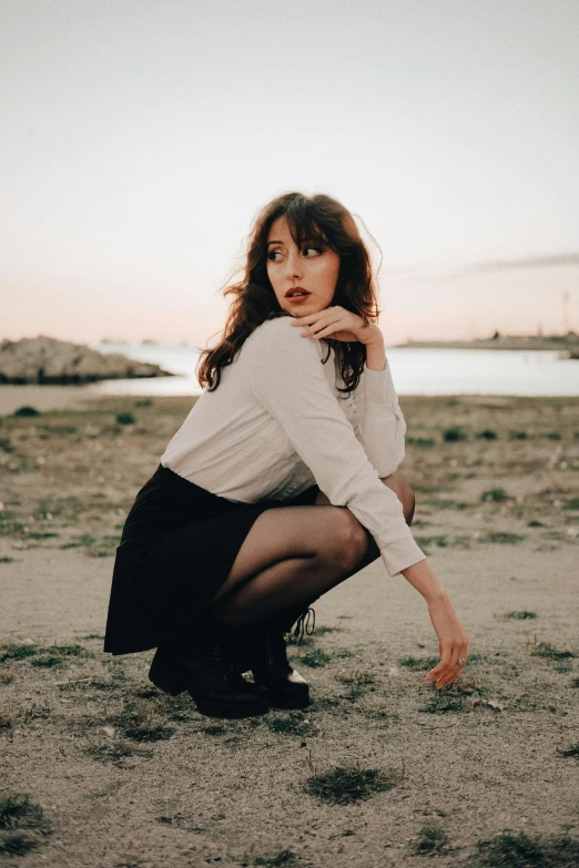 a woman kneeling in the sand wearing boots