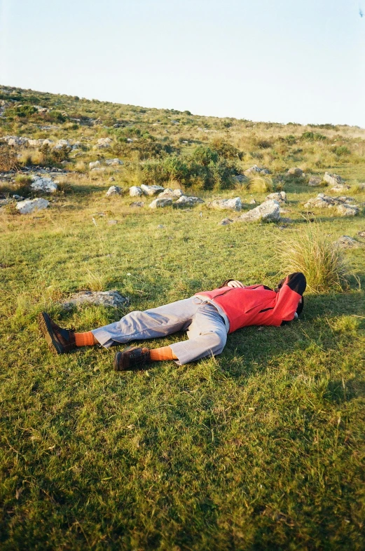 a man lying on a grassy field under a clear sky