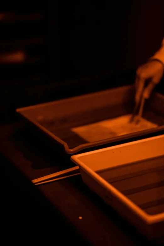 a person holds a square knife while placing a dish in a tray