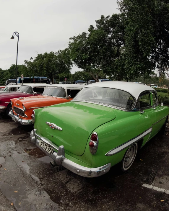 a green old car sitting in a parking lot