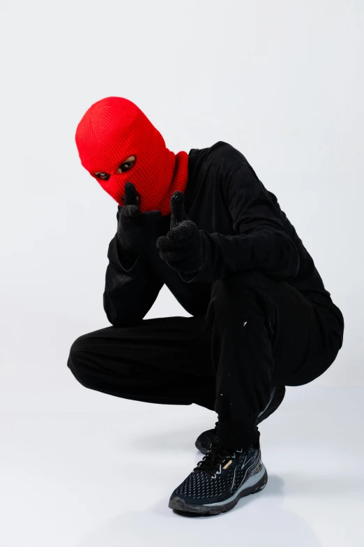 a person kneeling down wearing a red mask