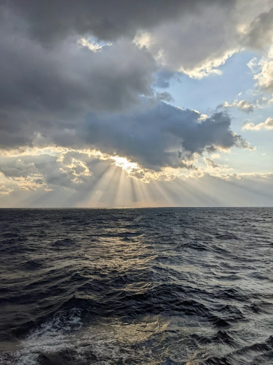 a sunbeam shining down through the clouds over the water