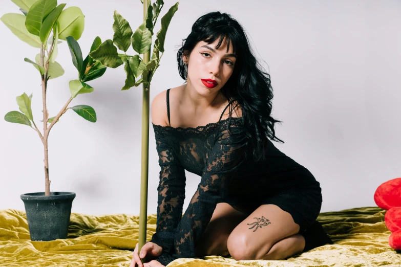 a woman kneeling next to a plant on a yellow blanket