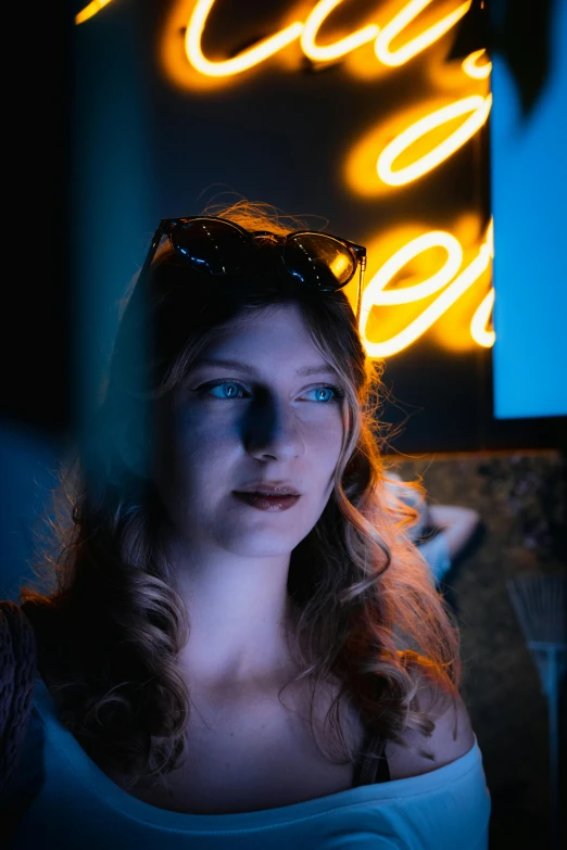 a woman with glasses in the dark standing next to a neon sign