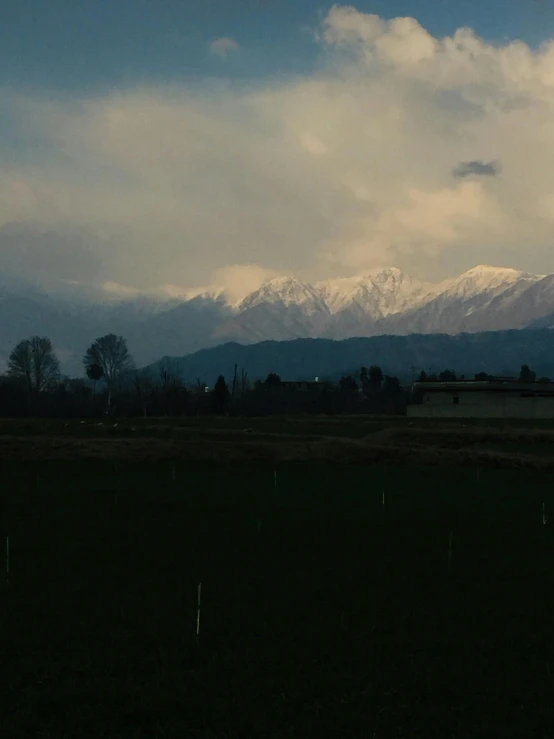 a house and a pasture with snowy mountains in the background