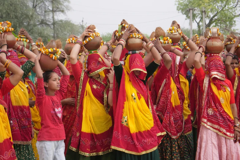 a group of women in colorful dress carrying pots