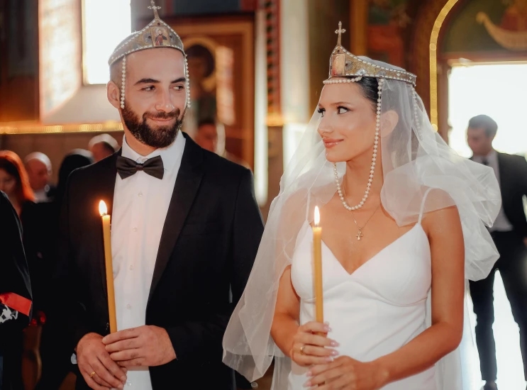 a bride and groom in tuxedo holding candles