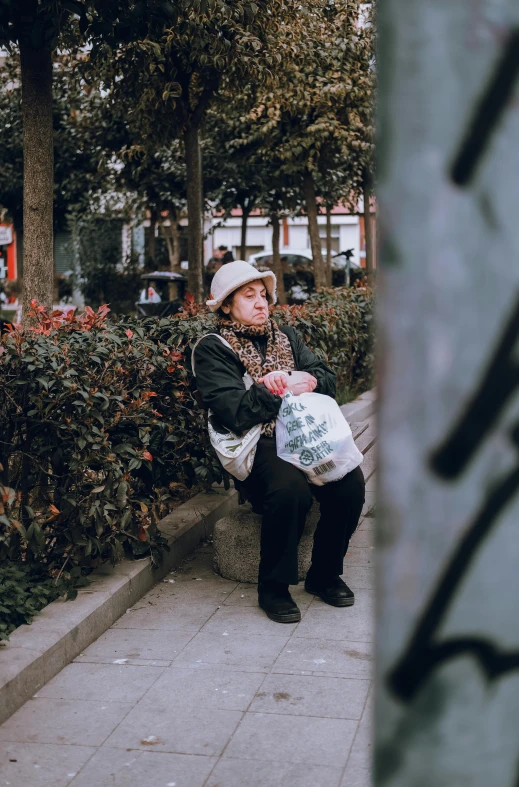 a woman in a white hat sitting on a stone bench