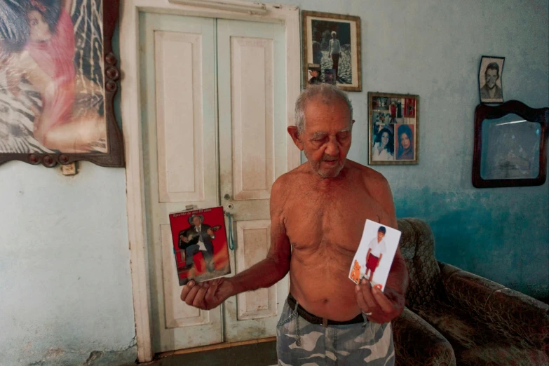 an old man in a blue room holding a book