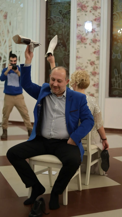 a man sitting on a chair holding soing in the air