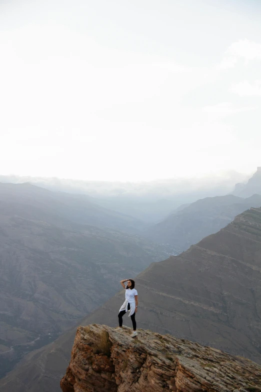 a person stands on the edge of a mountain holding his arms up