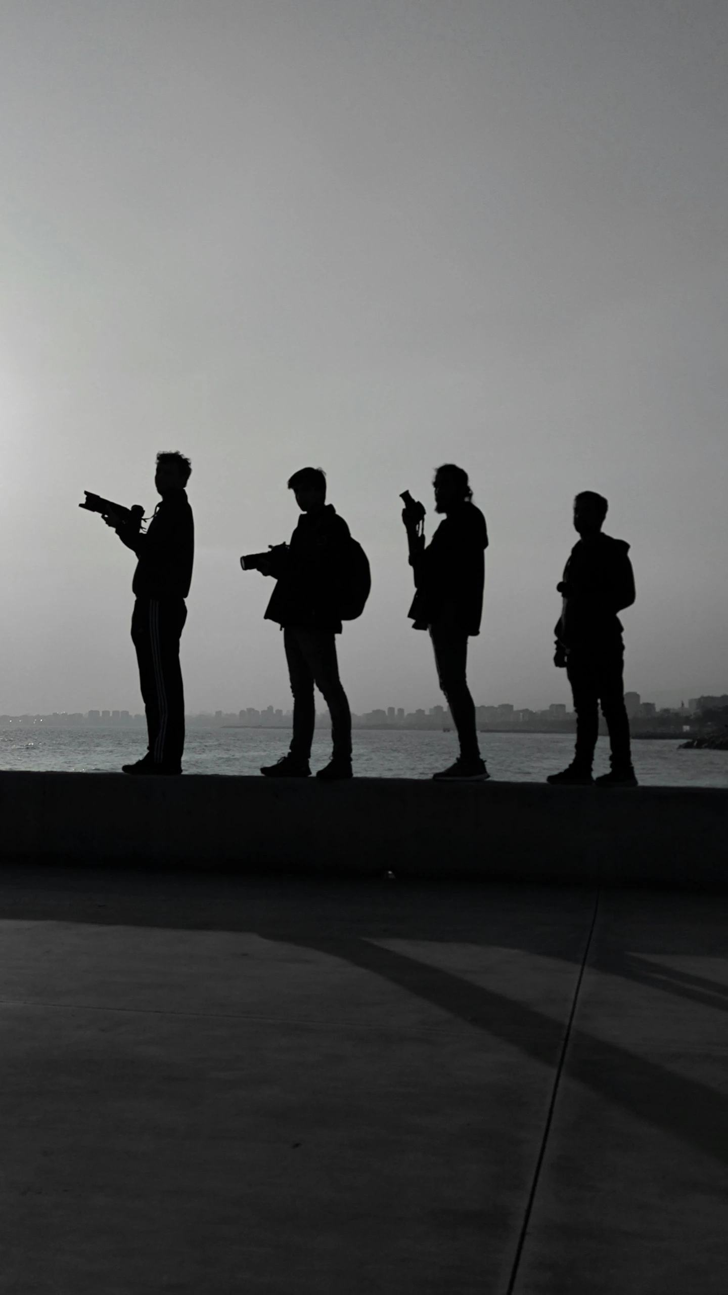 five people standing by the ocean talking to each other