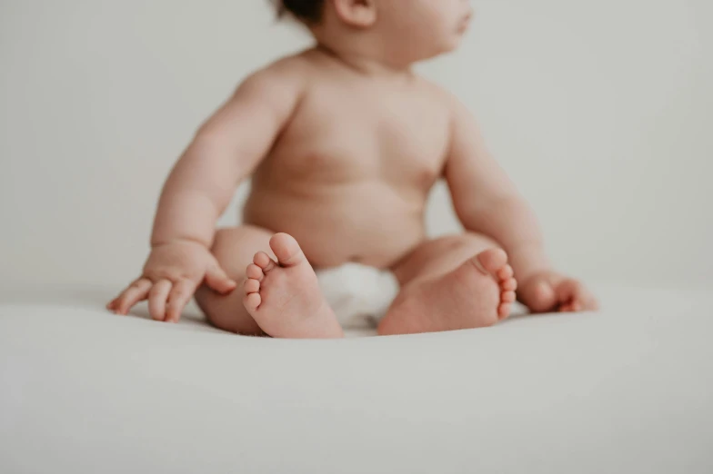 a small baby sitting on the floor with a white blanket