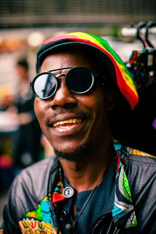 a smiling man in a colorful hat and sunglasses