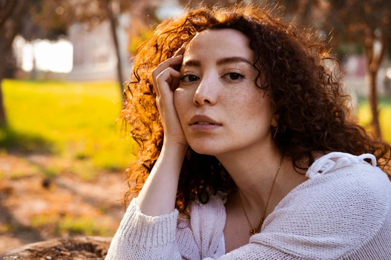 a woman with curly hair is sitting outside