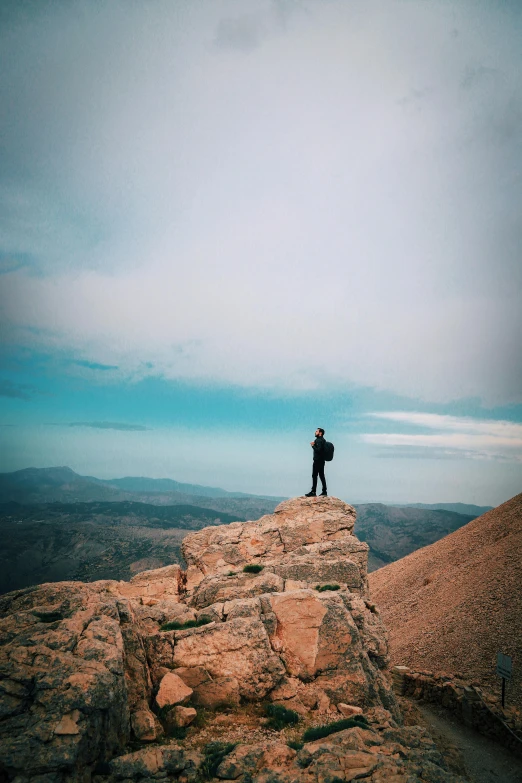 person standing on a rocky mountain top, with a camera