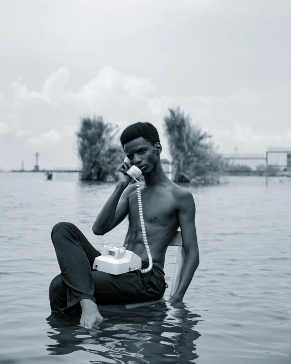 a man sits in a body of water while on the phone