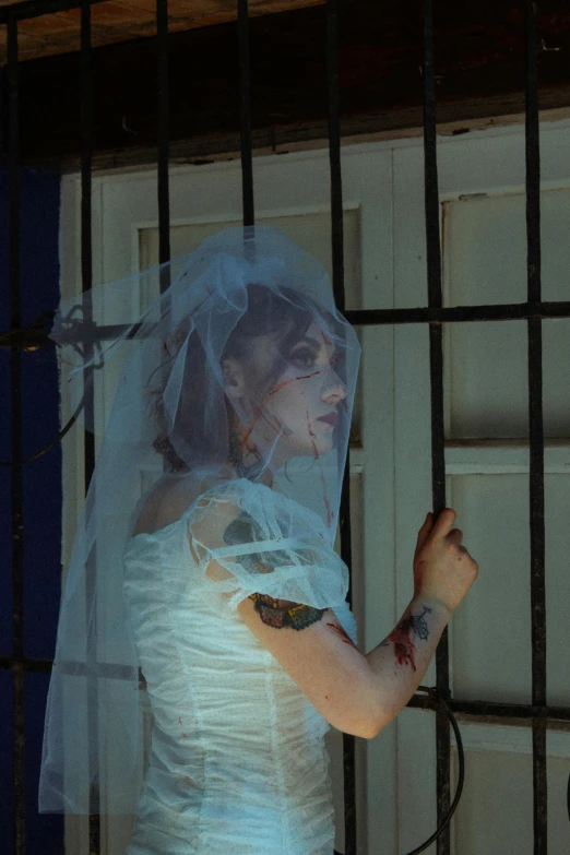 the bride stands in front of a bar fence with her veil down