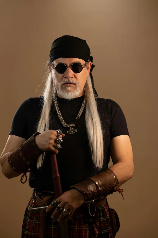 a man wearing glasses with long white hair, black shirt, and a large silver chain and leather gloves