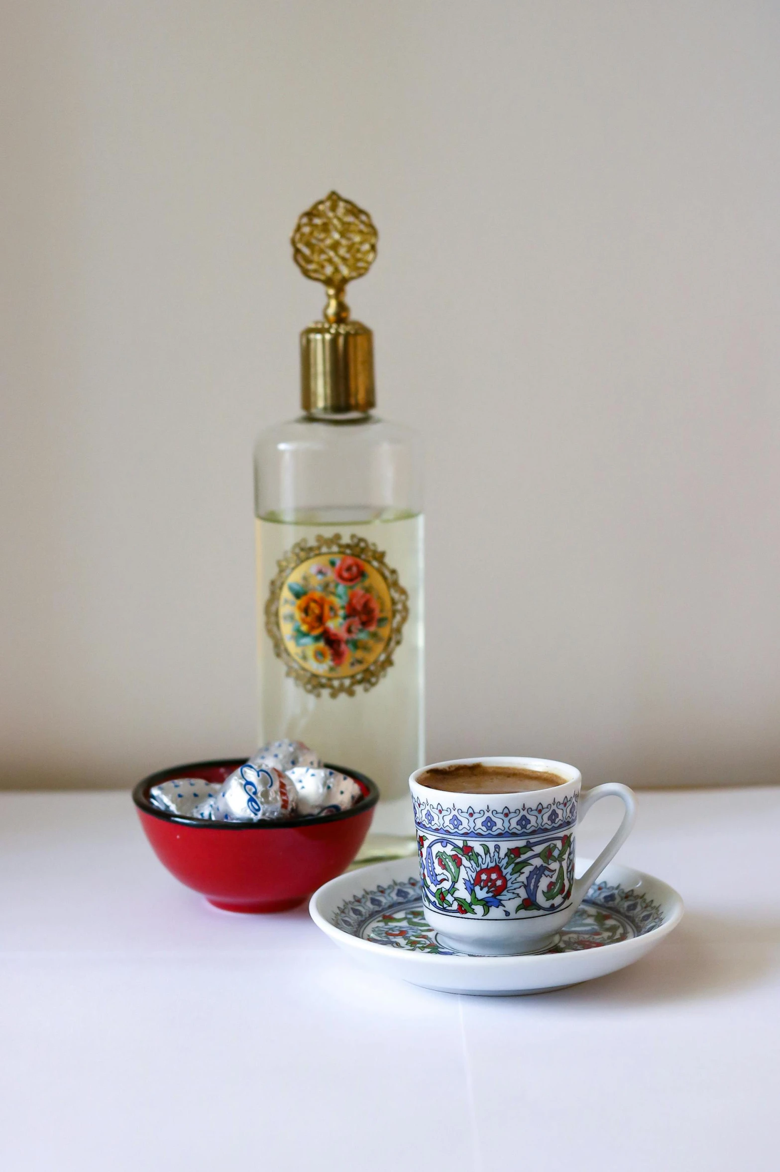 a tea cup with a small saucer on a saucer sits next to a bottle