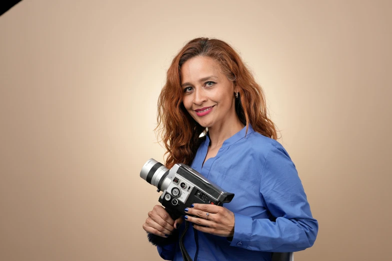 a woman holds a camera and smiles