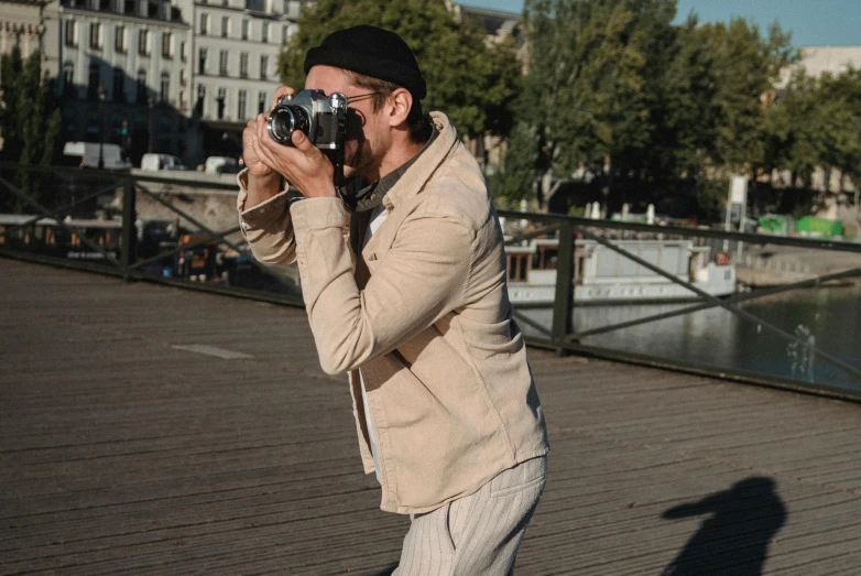 a man holding a camera standing on a pier