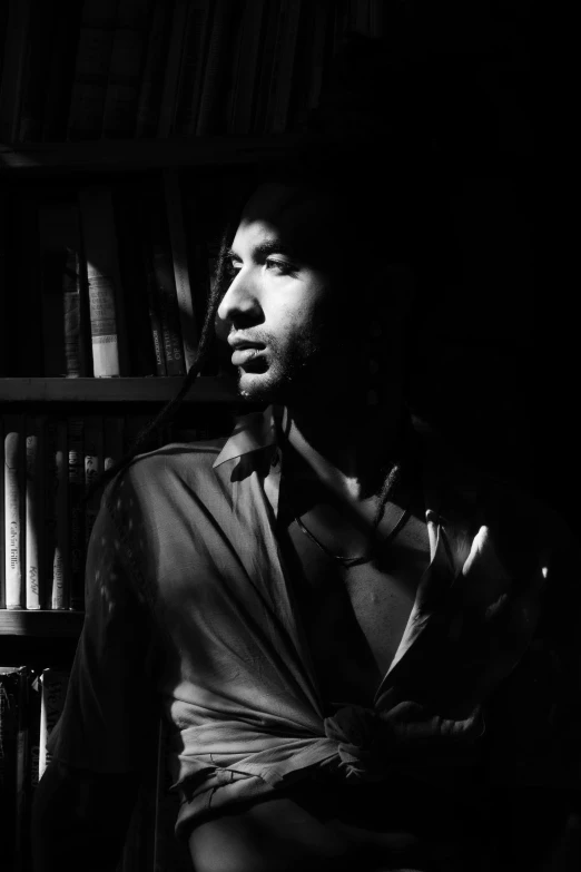 a man in a shirt and tie stands in a room with books