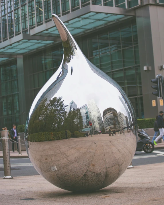 large metal sculpture on street with people walking in front