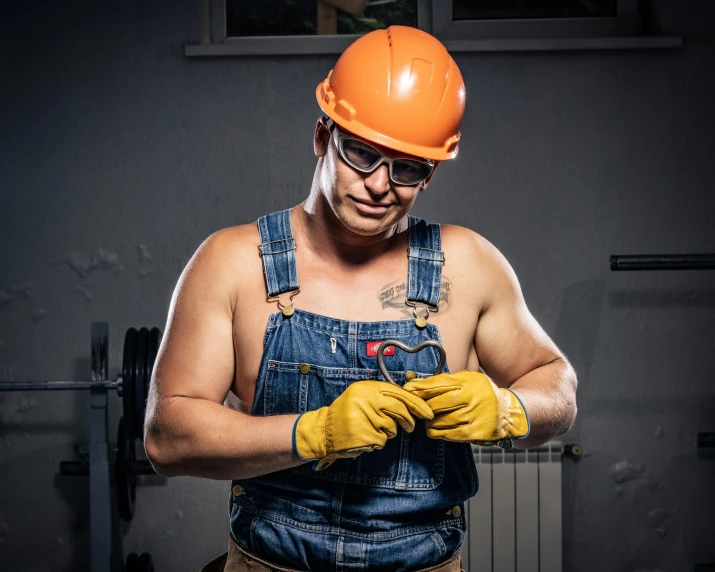 a man with a hard hat and orange safety glove on holding a piece of wood