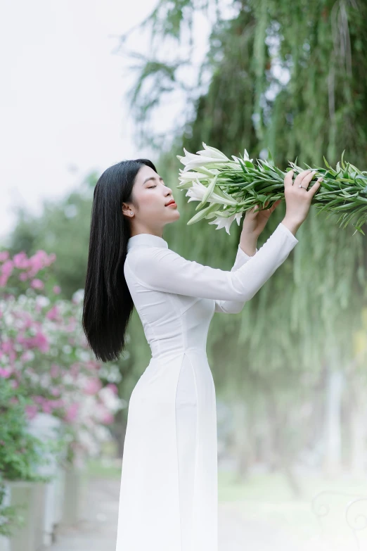 a woman in white is holding a bunch of flowers