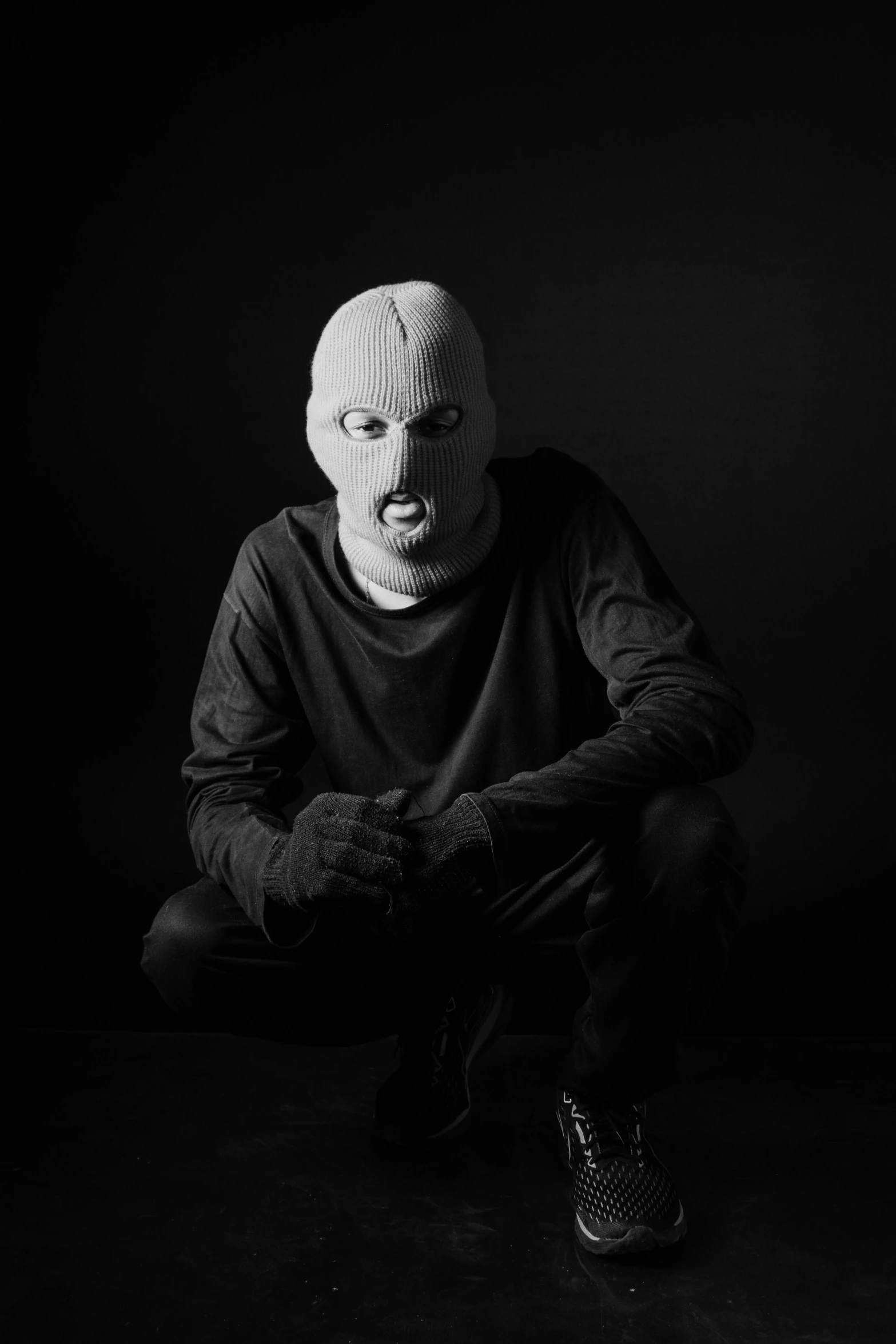 man in a mask sits on the floor with his foot propped up