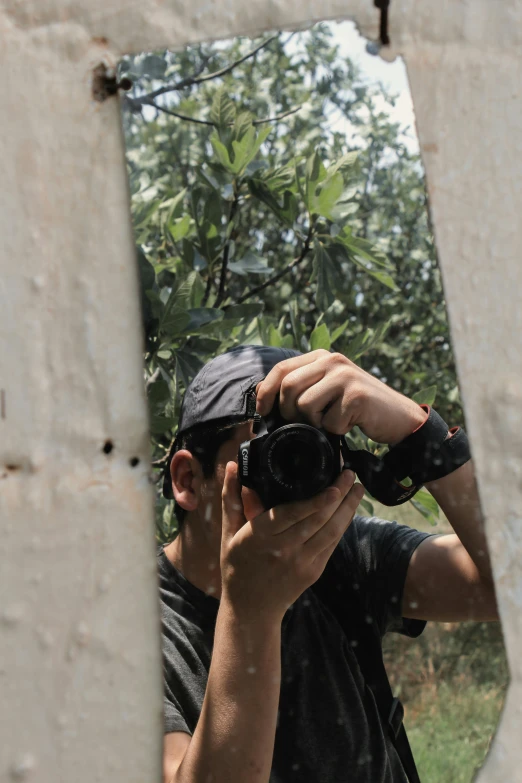 man taking picture of trees in a mirror