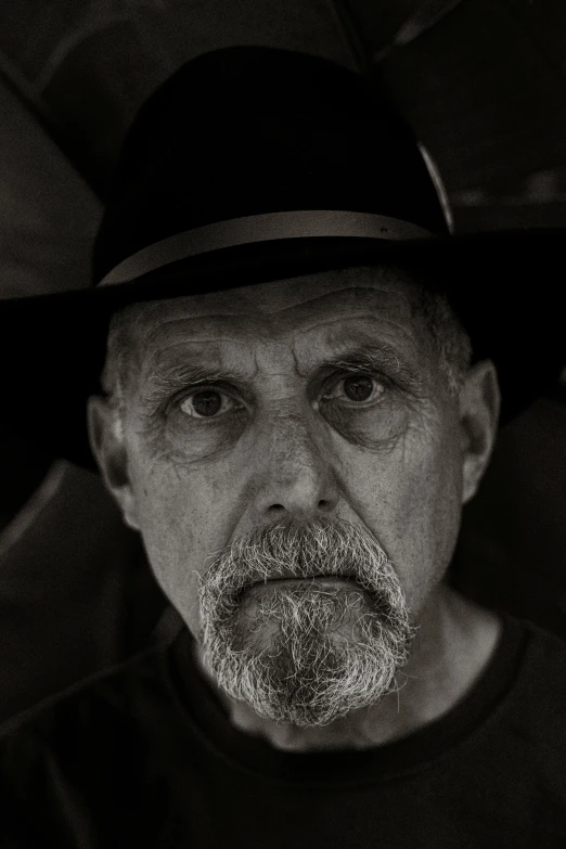 a man with a white beard and hat standing next to a wall