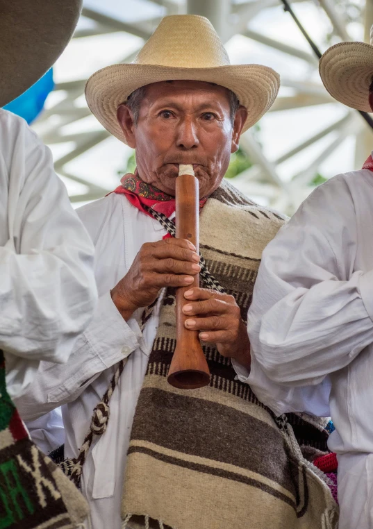 an old man wearing a white hat holding a musical instrument